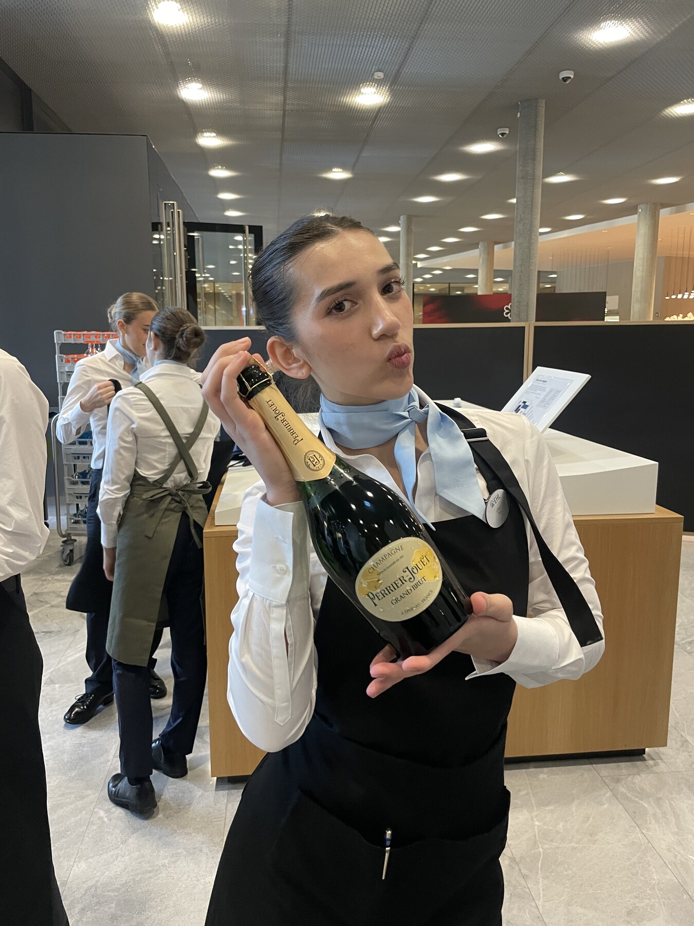 Lillian in her EHL service uniform holding a champagne bottle